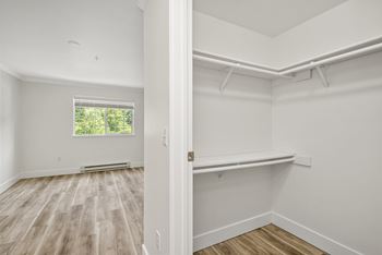 A room with white walls and wooden flooring with a window. at Lakemont Orchard Apartments, Issaquah , Washington